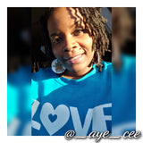 Bourgeois Pineapples owner Ayesha Clarke wearing multi color Blue White Yellow Orange and Purple wood earrings with Black Girl Magic and afro hair pick. She's wearing LOVE Over Everything hoodie from @DoeNation804